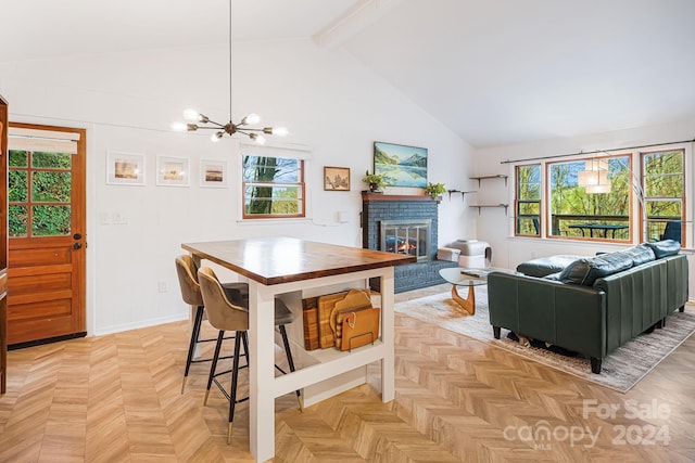 dining area with beam ceiling, a fireplace, light parquet flooring, and an inviting chandelier