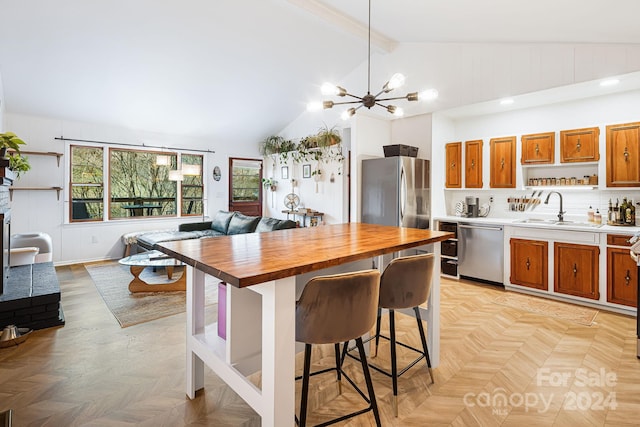 kitchen with a kitchen bar, appliances with stainless steel finishes, sink, decorative light fixtures, and butcher block counters