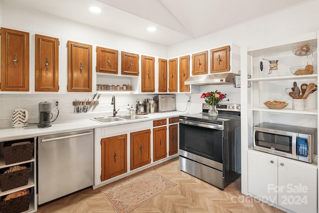 kitchen featuring sink, backsplash, light parquet floors, lofted ceiling, and appliances with stainless steel finishes