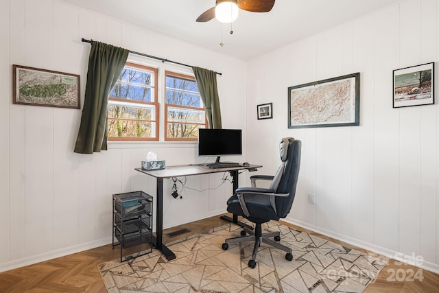 office space with light parquet flooring, ceiling fan, and wood walls