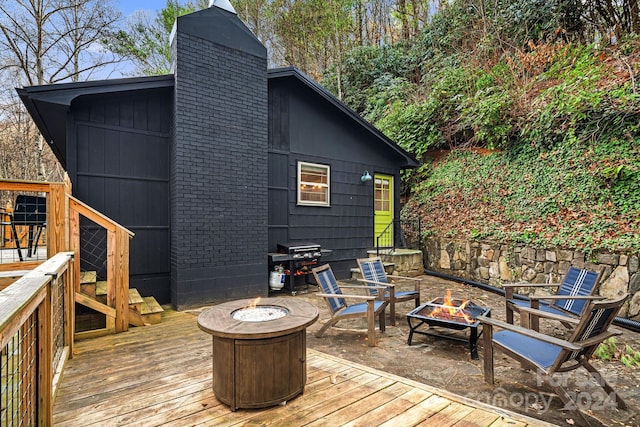 wooden terrace featuring area for grilling and an outdoor fire pit