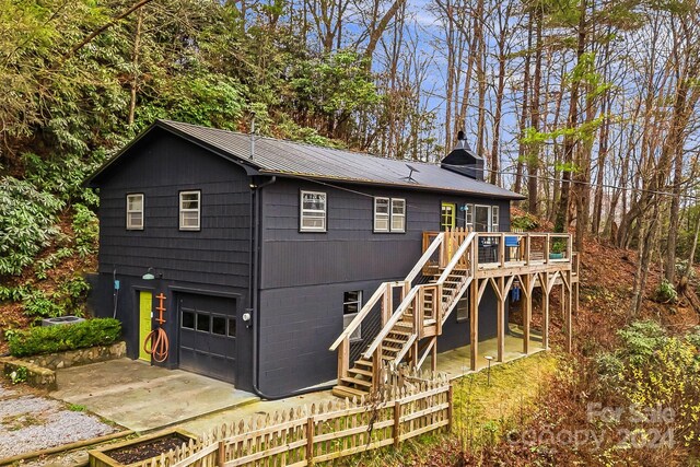 rear view of property with a garage and a wooden deck