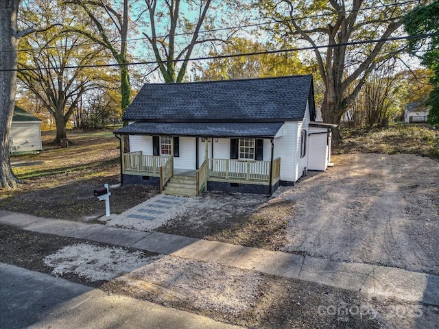 view of front of home with crawl space, covered porch, a shingled roof, and driveway