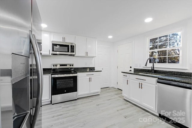 kitchen featuring light wood-style flooring, appliances with stainless steel finishes, white cabinetry, and a sink