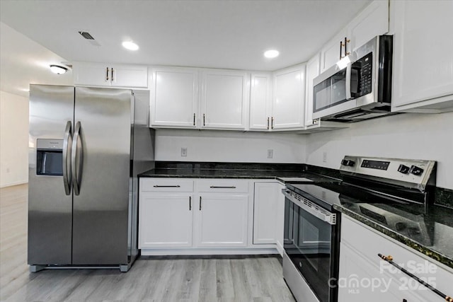 kitchen with dark stone countertops, recessed lighting, appliances with stainless steel finishes, white cabinets, and light wood finished floors