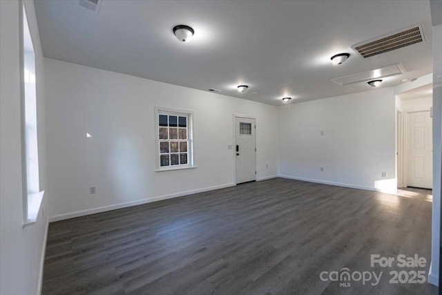 spare room with visible vents, attic access, dark wood-type flooring, and baseboards