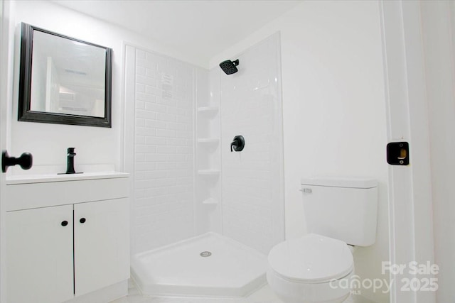 bathroom featuring a tile shower, toilet, and vanity