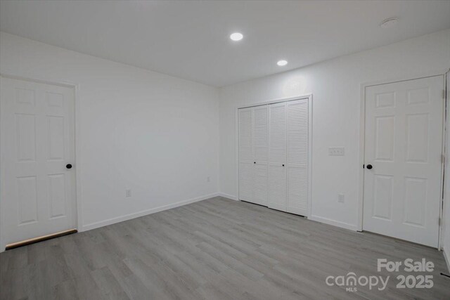 unfurnished bedroom featuring recessed lighting, a closet, baseboards, and wood finished floors