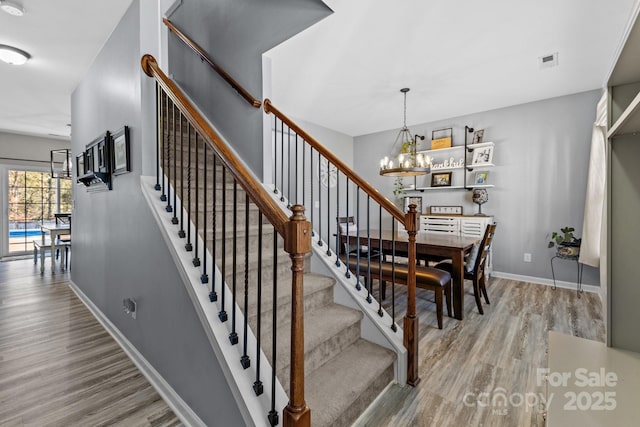 staircase with a chandelier and hardwood / wood-style flooring