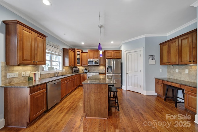 kitchen with sink, a breakfast bar area, stainless steel appliances, a center island, and dark stone counters