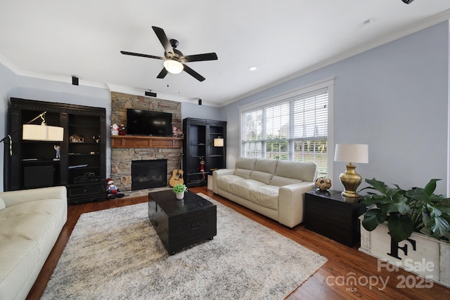 living room featuring ceiling fan, a fireplace, ornamental molding, and dark hardwood / wood-style floors