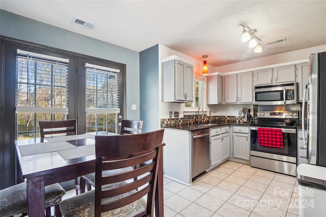 kitchen featuring gray cabinetry, sink, a textured ceiling, light tile patterned flooring, and appliances with stainless steel finishes