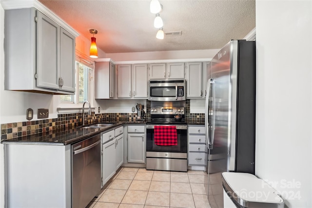 kitchen with a textured ceiling, stainless steel appliances, gray cabinetry, and sink