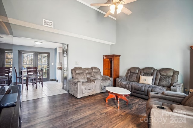 living room featuring hardwood / wood-style floors, ceiling fan, and a high ceiling