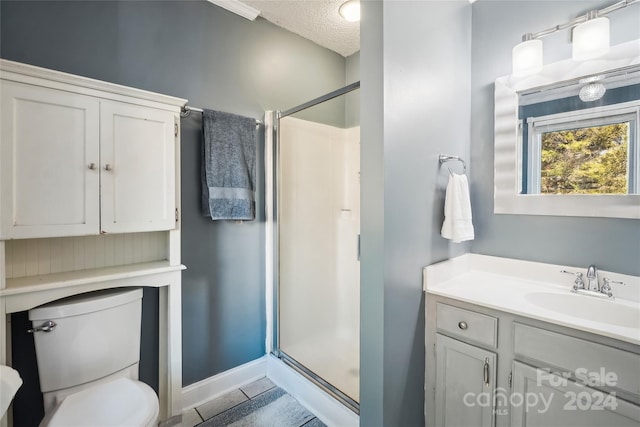 bathroom with vanity, tile patterned flooring, toilet, a textured ceiling, and walk in shower