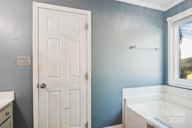 bathroom with a tub, vanity, a healthy amount of sunlight, and ornamental molding