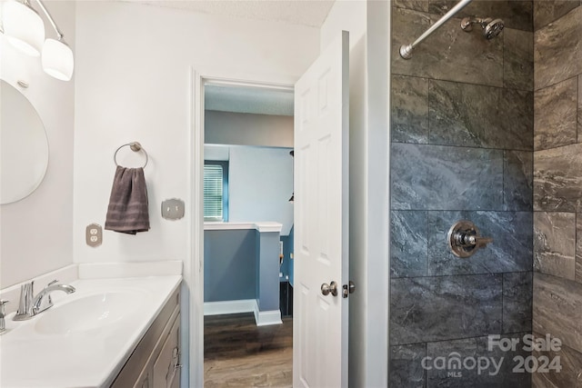 bathroom with vanity, wood-type flooring, a textured ceiling, and tiled shower