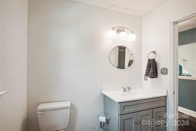 bathroom featuring vanity, a textured ceiling, and toilet