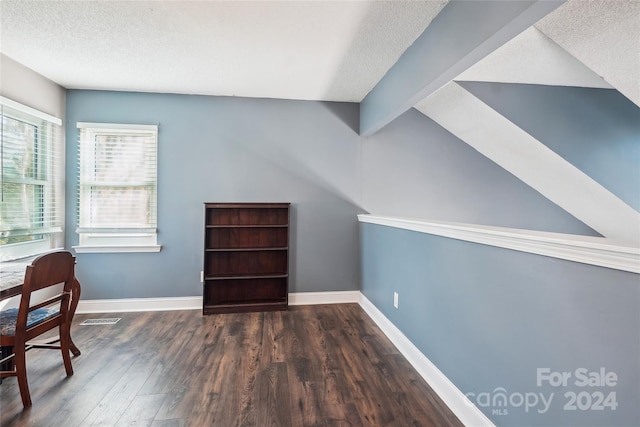 interior space with a textured ceiling, lofted ceiling with beams, and dark wood-type flooring