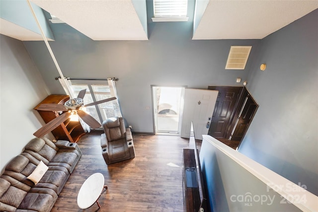 living room with a towering ceiling, dark hardwood / wood-style floors, and ceiling fan