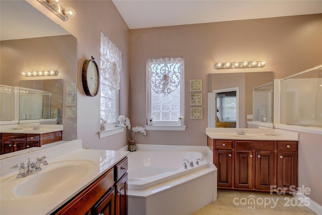 full bath with a stall shower, two vanities, a sink, and a bath