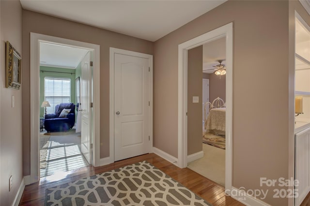 corridor with baseboards and wood finished floors