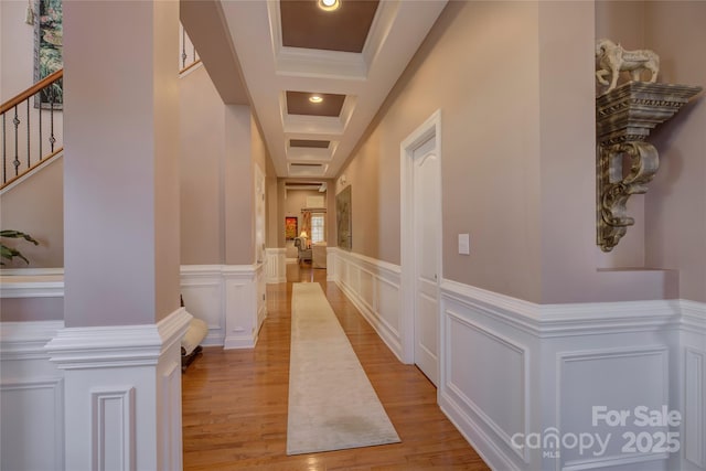 hallway featuring light wood-style flooring, recessed lighting, a decorative wall, stairs, and ornate columns