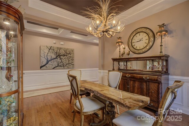 dining room featuring light wood-type flooring, a wainscoted wall, a decorative wall, and an inviting chandelier