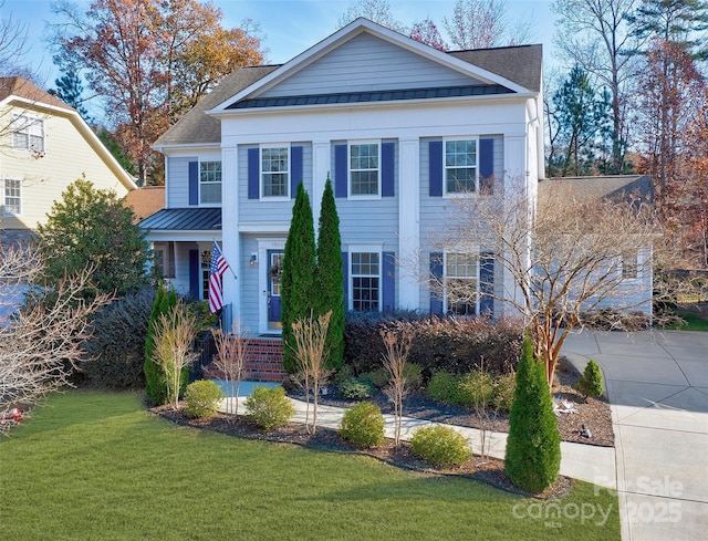 neoclassical / greek revival house with a shingled roof, concrete driveway, a front yard, a standing seam roof, and metal roof