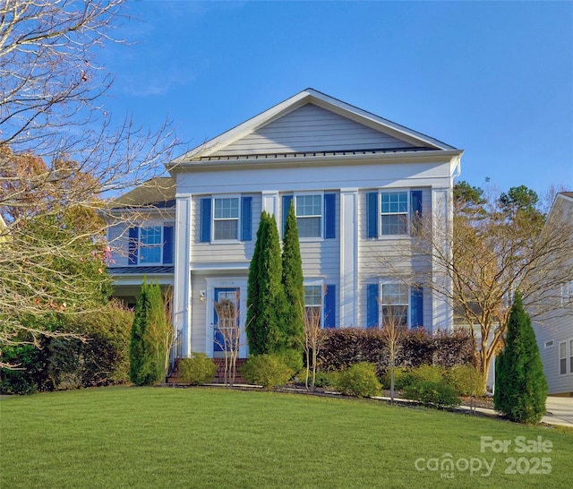 neoclassical / greek revival house featuring a standing seam roof, metal roof, and a front lawn