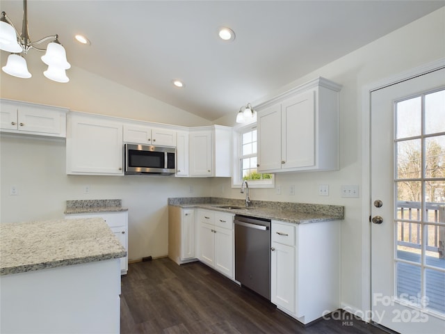 kitchen with appliances with stainless steel finishes, vaulted ceiling, white cabinetry, and a notable chandelier