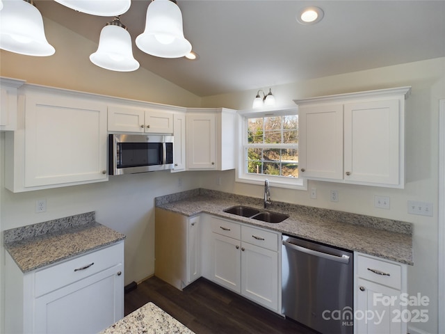 kitchen featuring white cabinetry, sink, stainless steel appliances, lofted ceiling, and decorative light fixtures