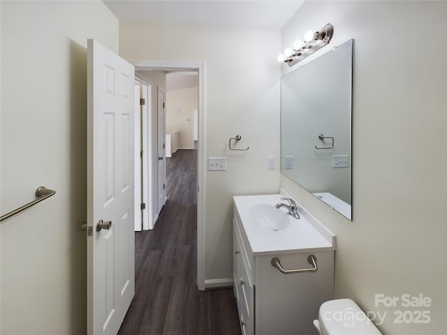 bathroom with toilet, vanity, and hardwood / wood-style flooring