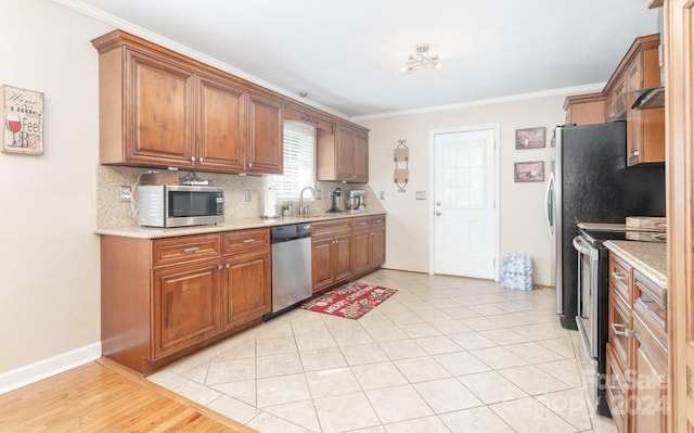 kitchen with appliances with stainless steel finishes, tasteful backsplash, ornamental molding, and light tile patterned flooring