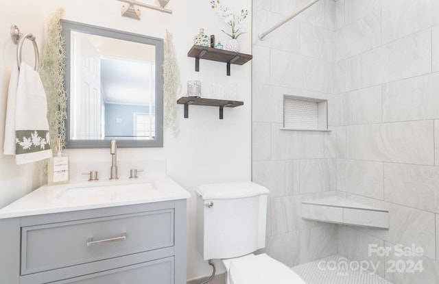 bathroom with tiled shower, vanity, and toilet