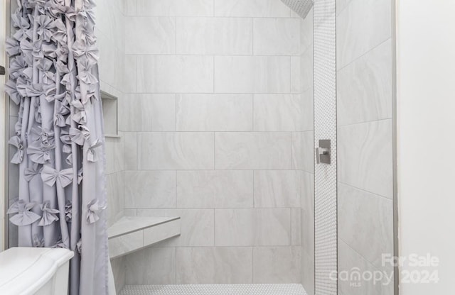 bathroom with tiled shower and toilet