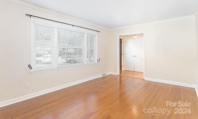 empty room with ornamental molding and hardwood / wood-style flooring