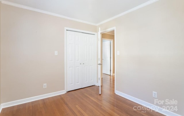 unfurnished bedroom with crown molding and hardwood / wood-style floors