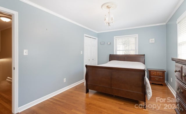 bedroom featuring an inviting chandelier, light hardwood / wood-style flooring, a closet, and crown molding