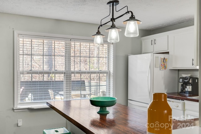 kitchen with white cabinets, plenty of natural light, white appliances, and butcher block counters