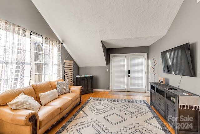 living room with light hardwood / wood-style floors, lofted ceiling, and a textured ceiling