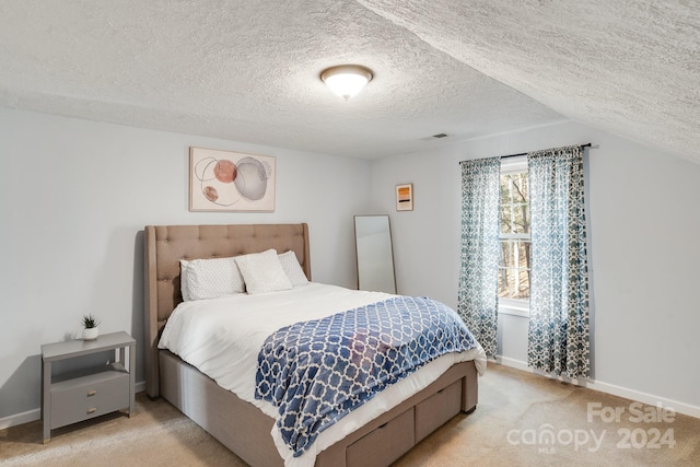 carpeted bedroom with a textured ceiling and vaulted ceiling