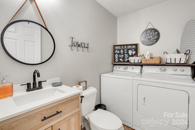 bathroom featuring vanity, toilet, separate washer and dryer, and a textured ceiling