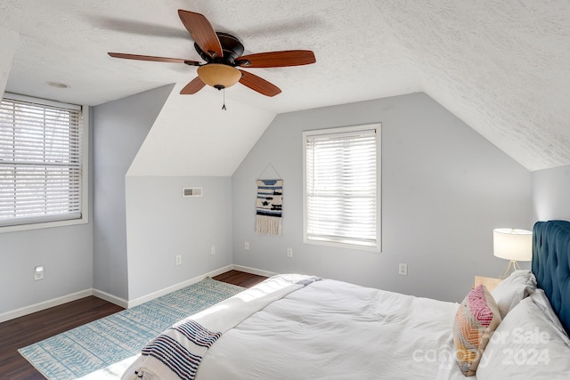 bedroom featuring multiple windows, ceiling fan, dark wood-type flooring, and a textured ceiling