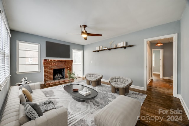 living room featuring dark hardwood / wood-style flooring, a brick fireplace, a wealth of natural light, and ceiling fan