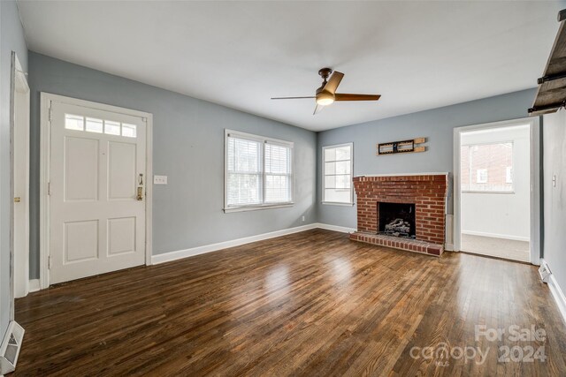 unfurnished living room featuring ceiling fan, dark wood-type flooring, and a brick fireplace