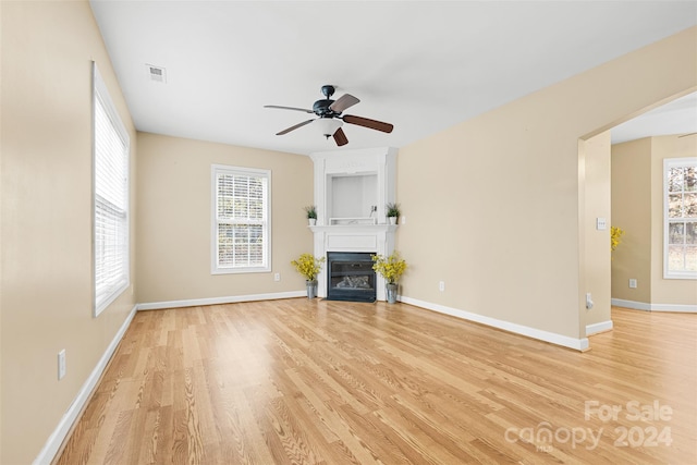 unfurnished living room with ceiling fan, light wood-type flooring, and a fireplace