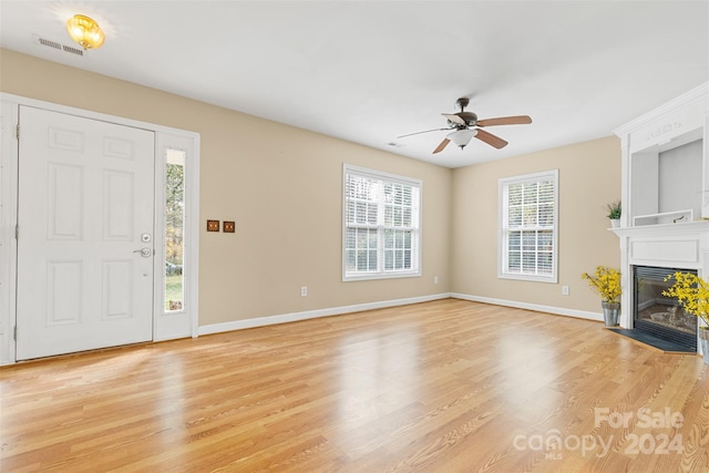 unfurnished living room featuring a fireplace, light hardwood / wood-style floors, and ceiling fan