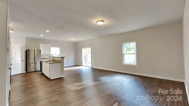 kitchen with a kitchen island with sink, sink, white cabinets, dark hardwood / wood-style floors, and stainless steel refrigerator