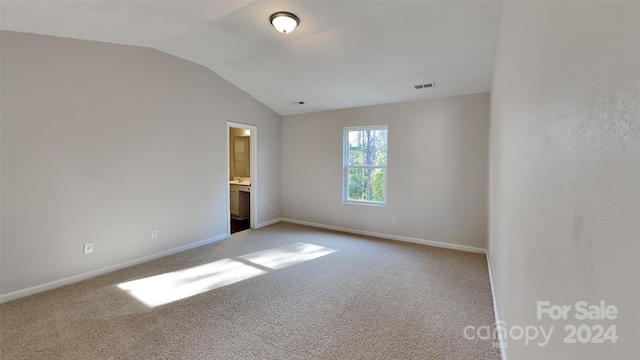 carpeted spare room featuring lofted ceiling